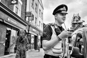 Street photography featuring a police officer and a teddy bear.