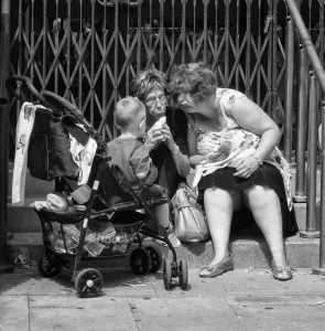 Street photography: Black and white photograph capturing two women and a child on steps.