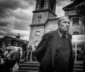 A street photographer capturing an old man in front of a church.