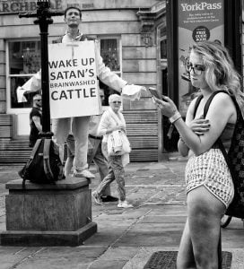 Street photography of a woman holding a sign that says wake up satan.