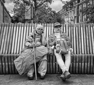 Street photography: a monochrome photo capturing two individuals seated on a bench.