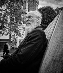 A bearded man captured in street photography while sitting on a bench.