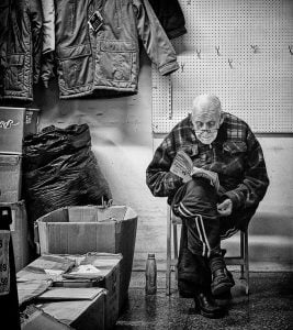An old man sitting in a chair reading a book.