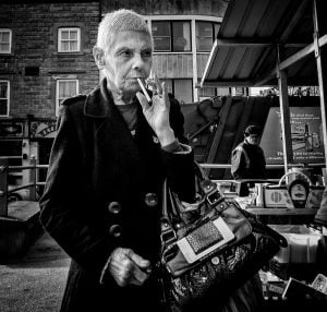 A woman captured through street photography smoking a cigarette.