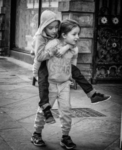 A street photography capturing two children playing on the street in black and white.