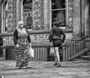 A monochrome street photography featuring a woman strolling down the street.