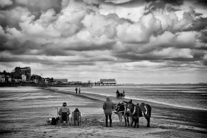 A black and white street photography of a group of people on a beach.