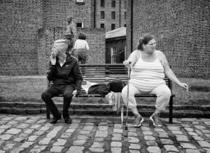 A street photography capturing two people sitting on a bench in black and white.