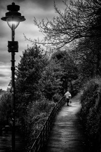 A black and white street photography of a man walking down a path.