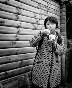 A woman savoring a cup of coffee in a street scene.