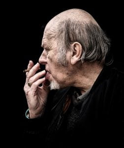 Street photography of a man smoking against a black background.