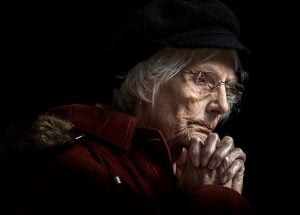 A portrait of an old woman in a red coat and hat.