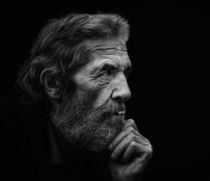 A street photography image featuring an elderly man with a beard, captured in monochrome.