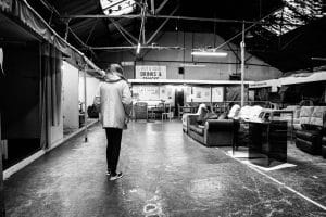 A street photography-style black and white photo of a man standing in an empty room.