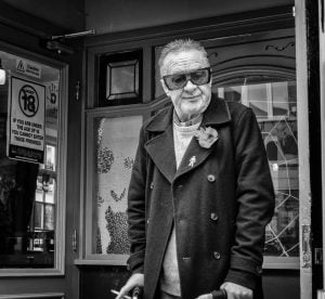 Street photography: A monochrome image capturing an aged man puffing on a cigarette