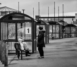 Street photography of a woman sitting at a bus stop bench.