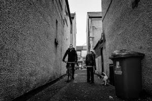 A black and white photograph of two people walking down a Rhyl alley.