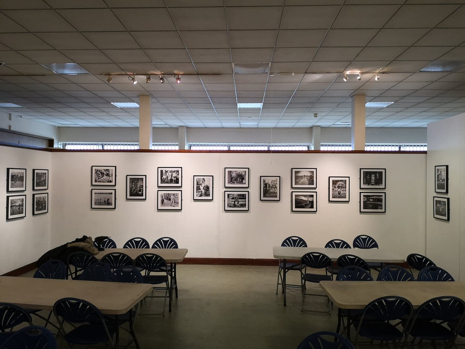 A room with tables and chairs adorned with framed street photographs.