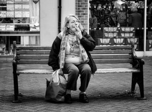 Street photography of a woman on a bench smoking.