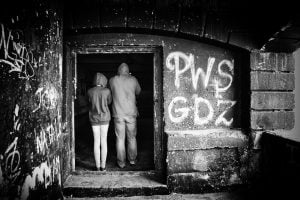 Street photography of two people standing in a doorway adorned with graffiti.