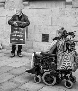 A man in a wheelchair holding a sign at Leeds Pride 2019, captured in stunning photographs.