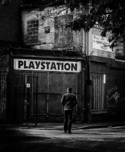 A monochrome street photography capturing a man at a Playstation store.
