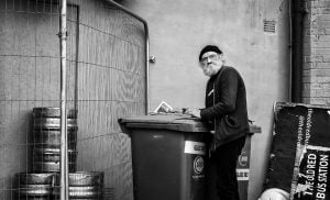 A man captured in street photography next to a trash can.