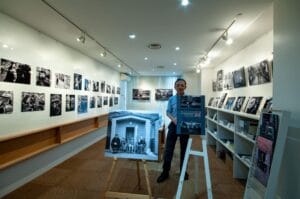 A man standing in front of a display of photos saying hello Tokyo.